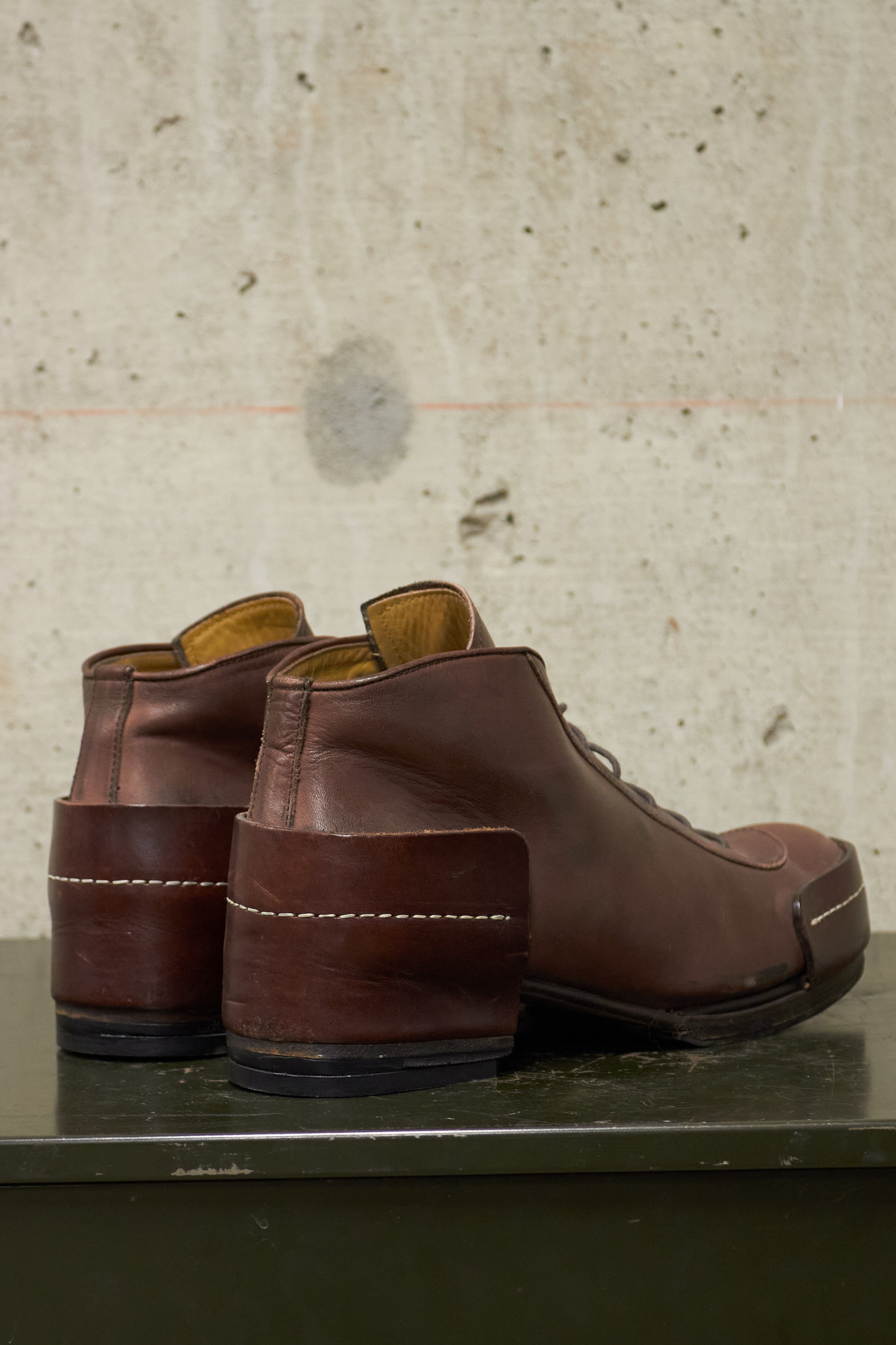 Pair of brown leather shoes on a concrete surface with a textured wall background