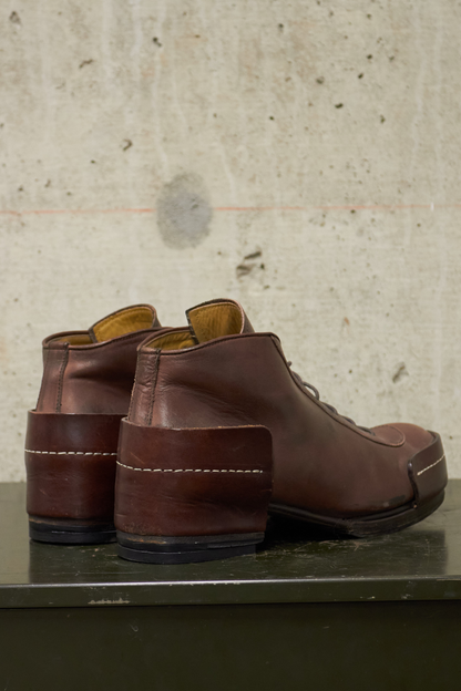 Pair of brown leather shoes on a concrete surface with a textured wall background