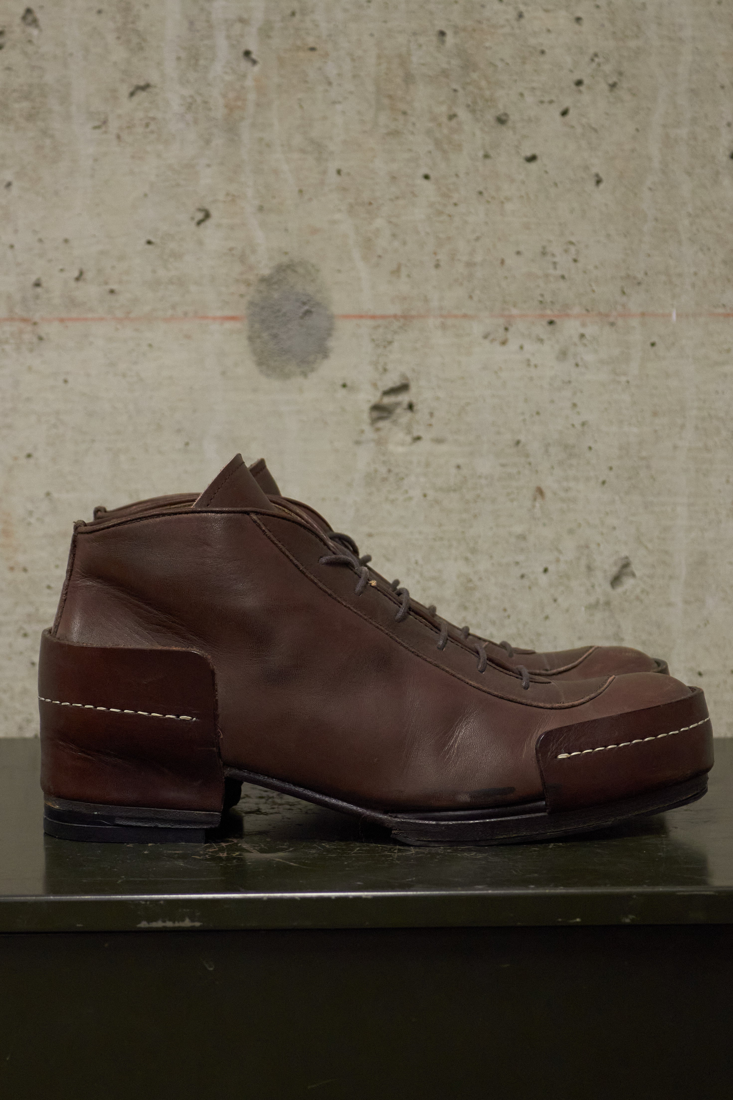 Brown leather shoe on a textured surface with a neutral background
