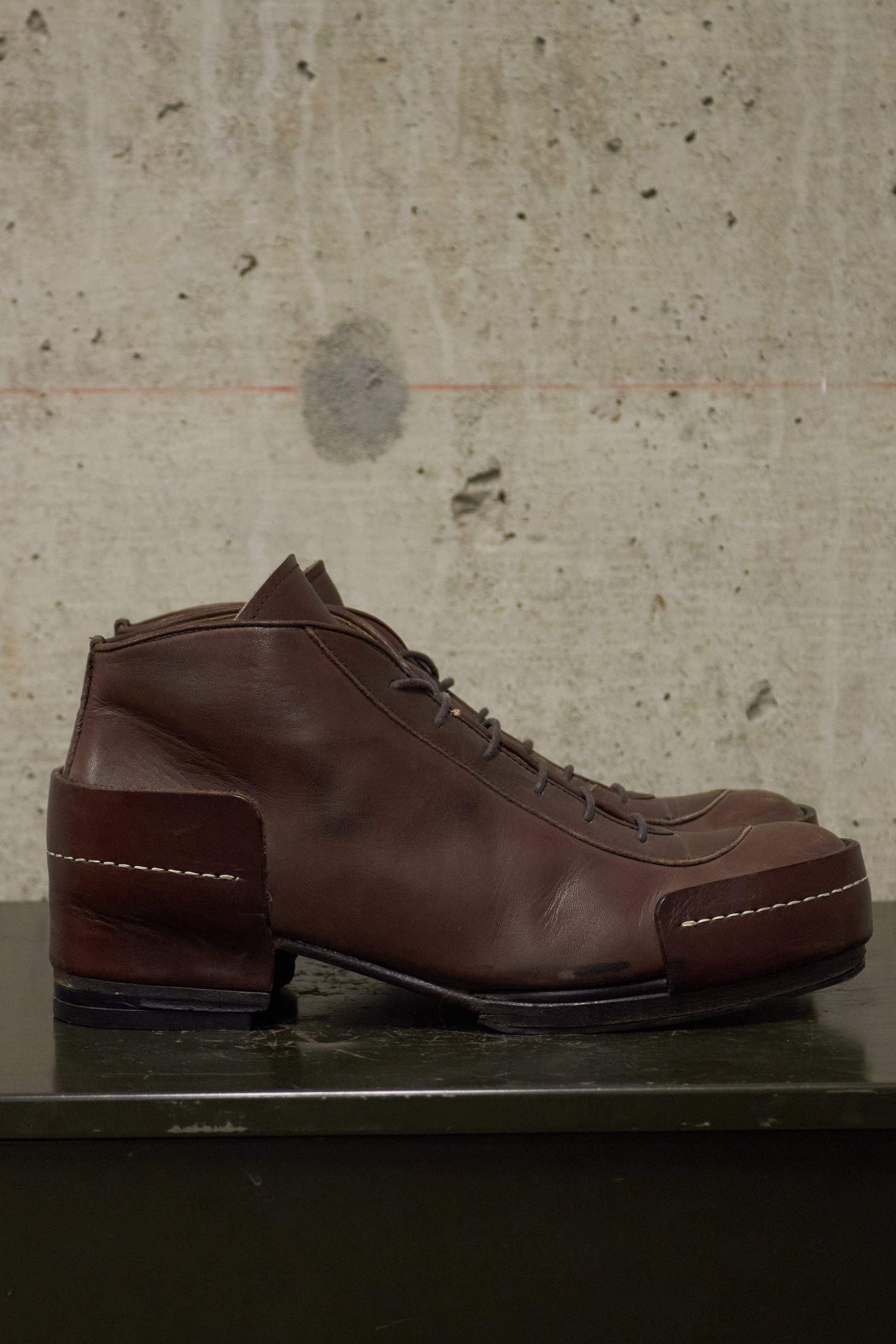 Brown leather shoe on a textured surface with a neutral background