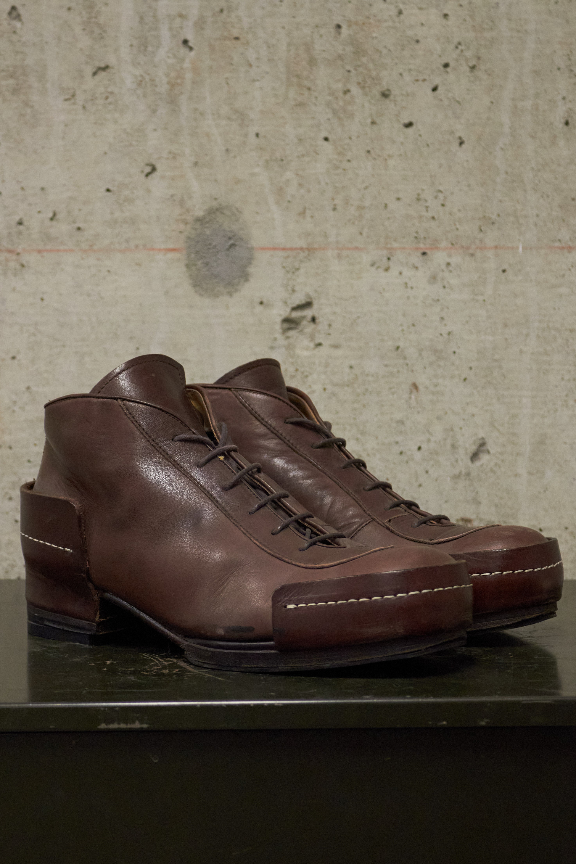 Pair of brown leather shoes on a textured surface with a concrete wall background