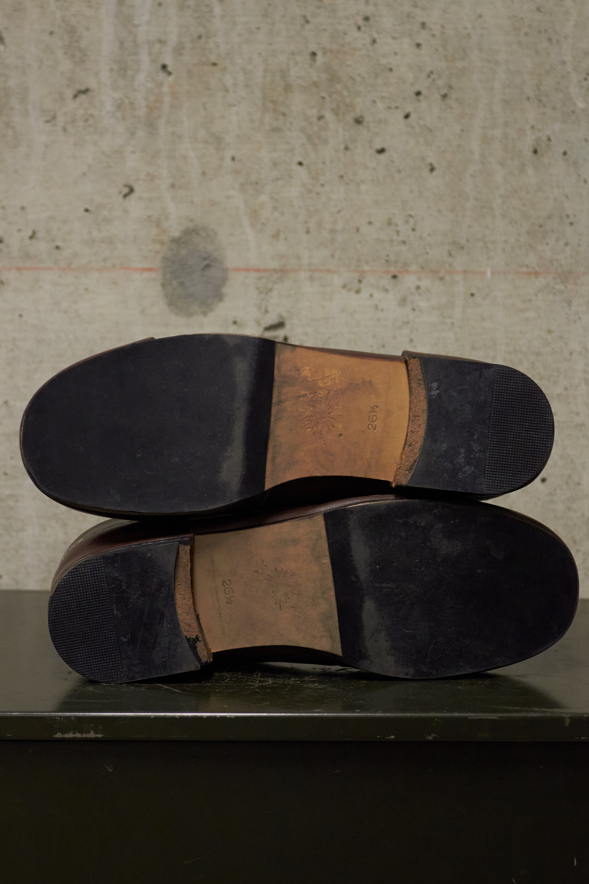 Close-up of black leather shoes with brown soles on a textured surface