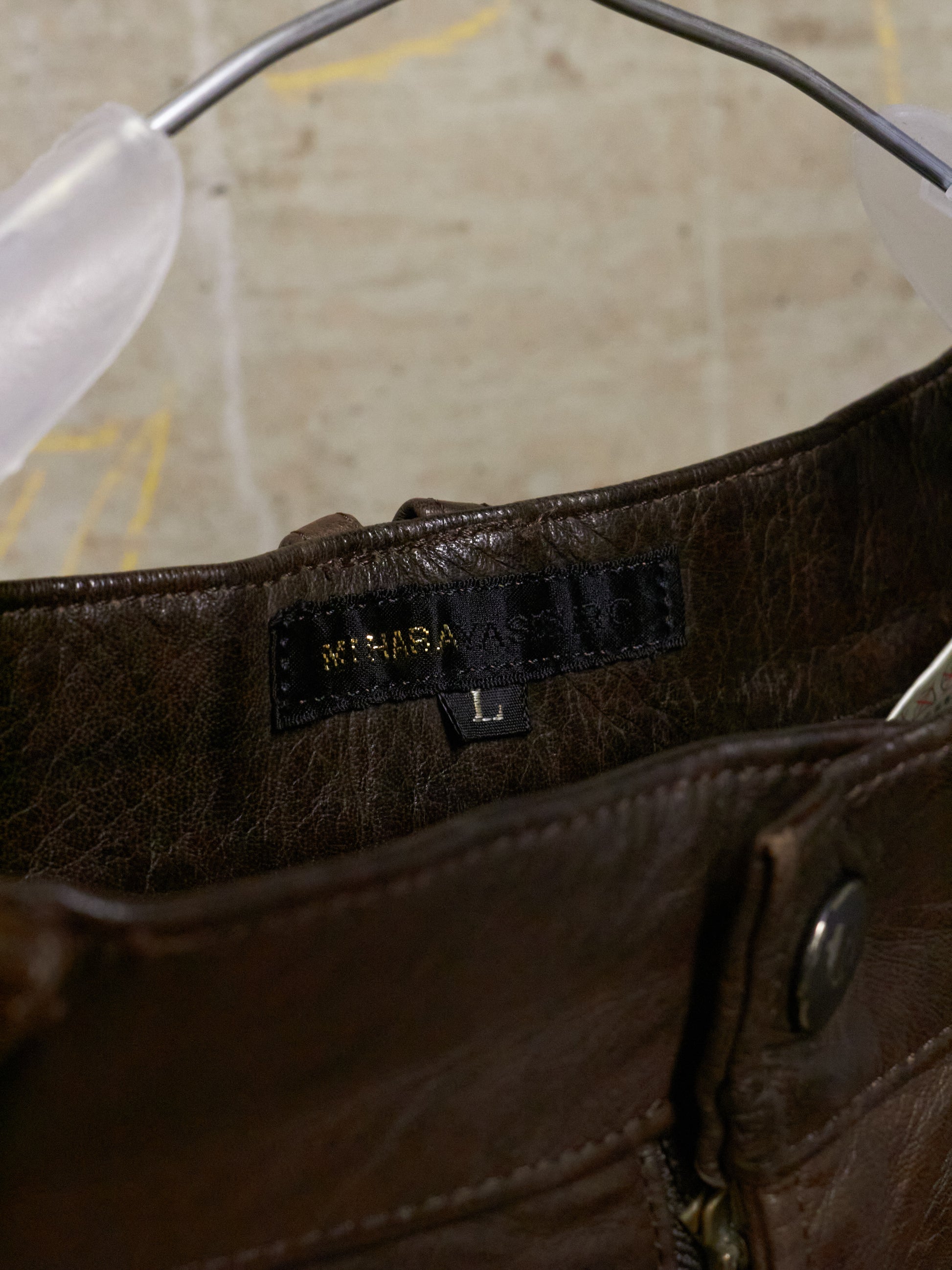 Close-up of a brown leather bag with a brand label on a neutral background