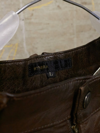 Close-up of a brown leather bag with a brand label on a neutral background
