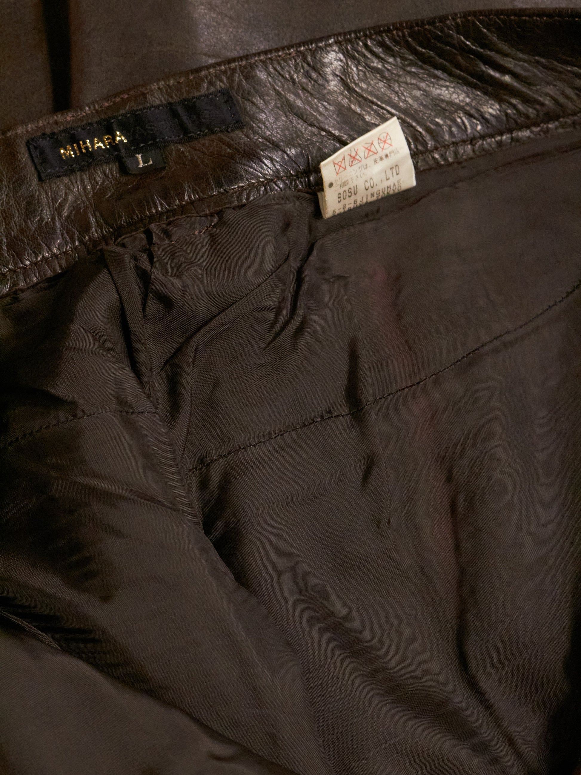 Close-up of dark brown pants with a brand label on the waistband.