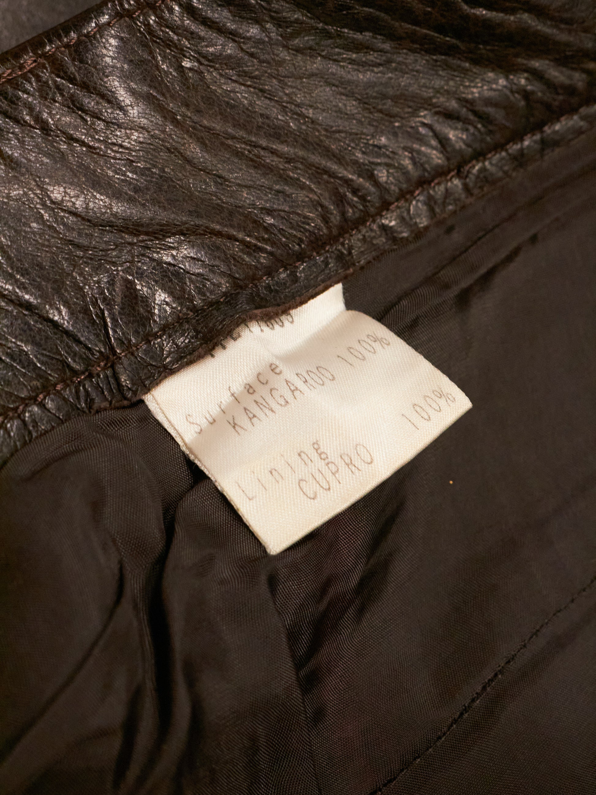 Close-up of a leather jacket with a brand label on a dark background