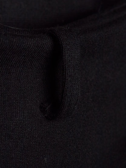 Close-up detail of a black knit garment showing the ribbed texture and a small loop detail.
