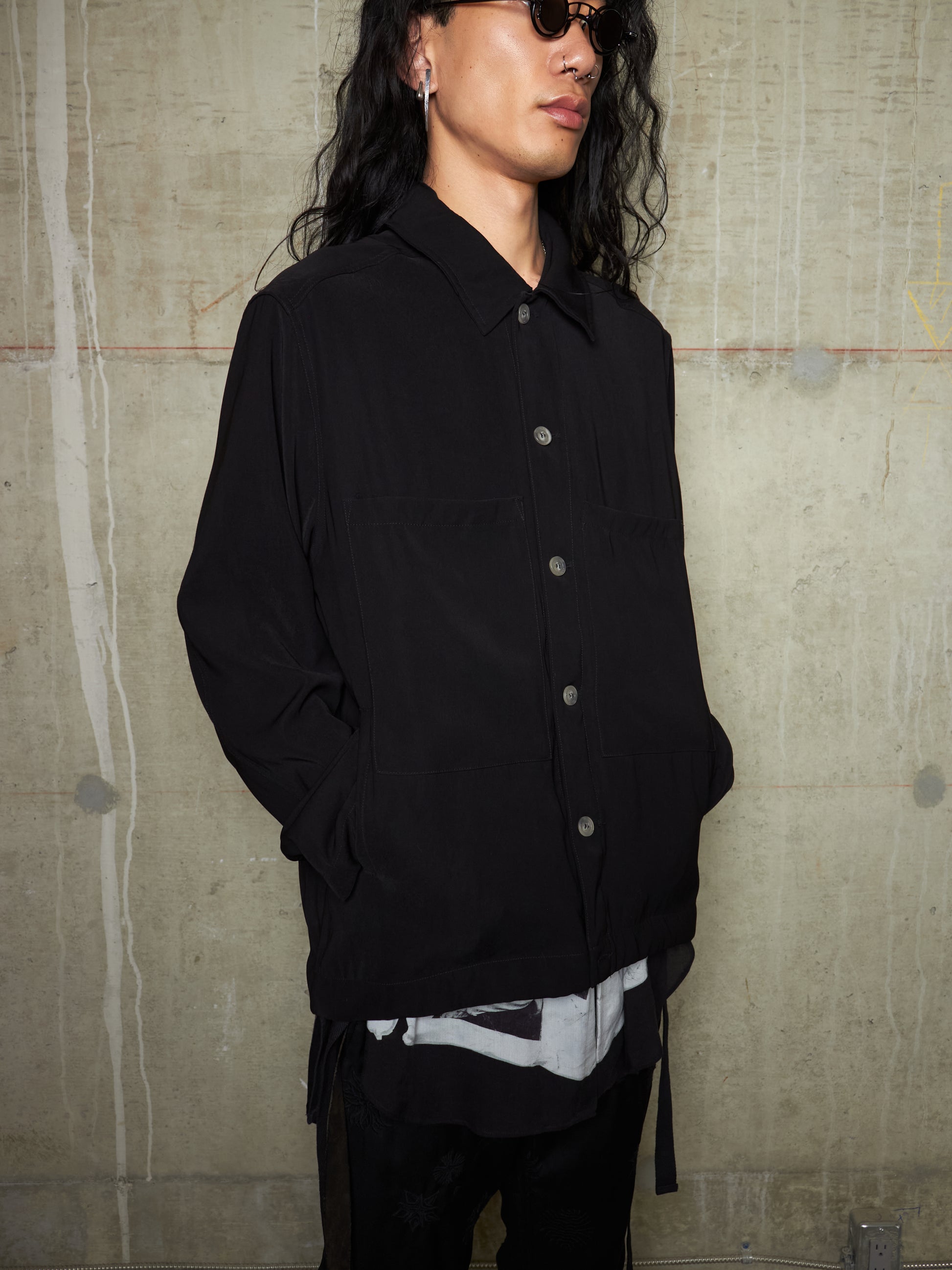 Person wearing a black jacket against a textured wall.