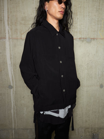 Person wearing a black jacket against a textured wall.