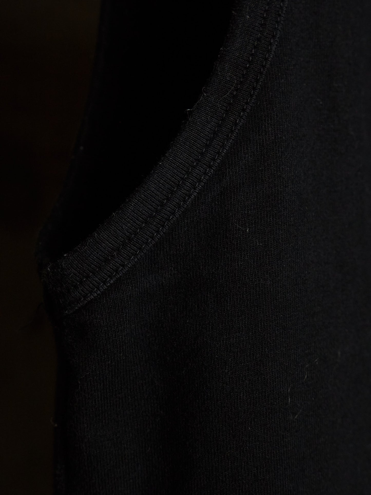 Close-up detail of a black ribbed knit garment, showing the texture and stitching of the collar or sleeve edge.