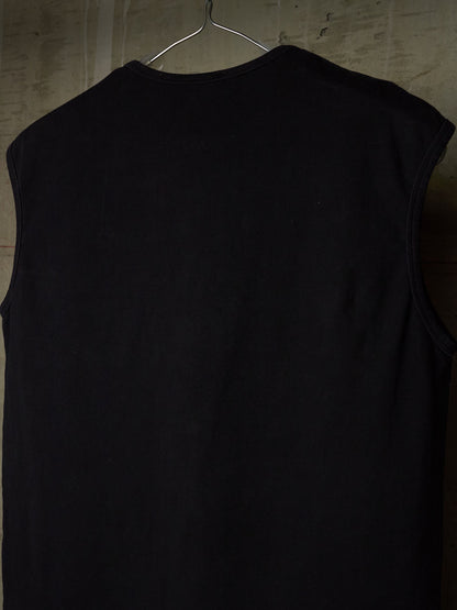 A black sleeveless ribbed tank top hanging on a metal hanger against a textured gray wall.