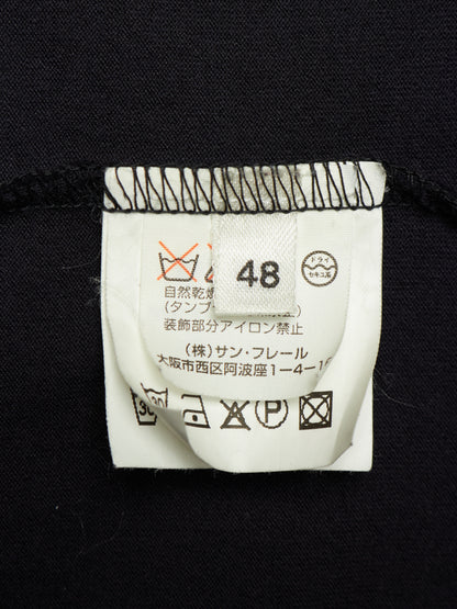 Close-up of a garment's white care label sewn onto black fabric, showing size 48 and Japanese care instructions.