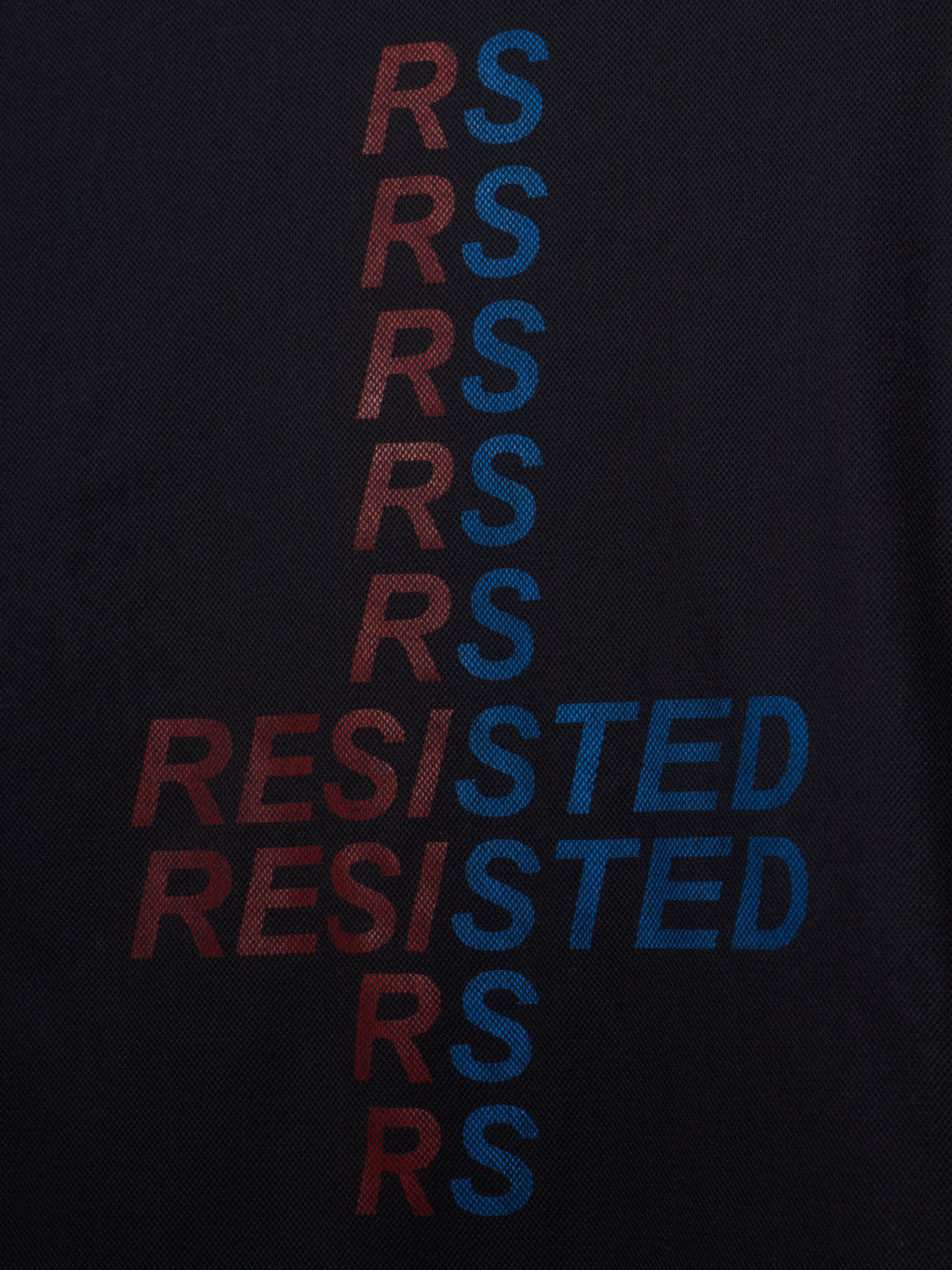 Close-up of a black textured fabric with a vertical graphic spelling 'RESISTED' in alternating red and blue letters.