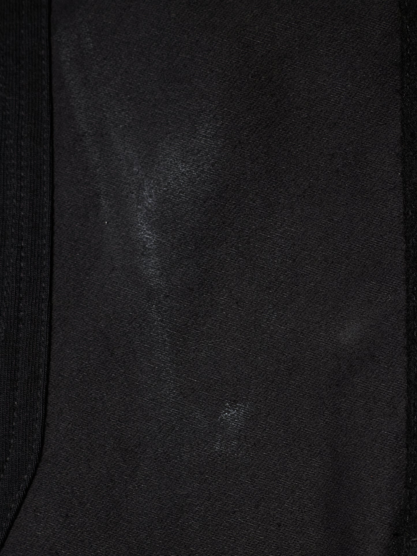 Close-up of a black fabric surface with a subtle sheen and a dark ribbed trim along the left and right edges.