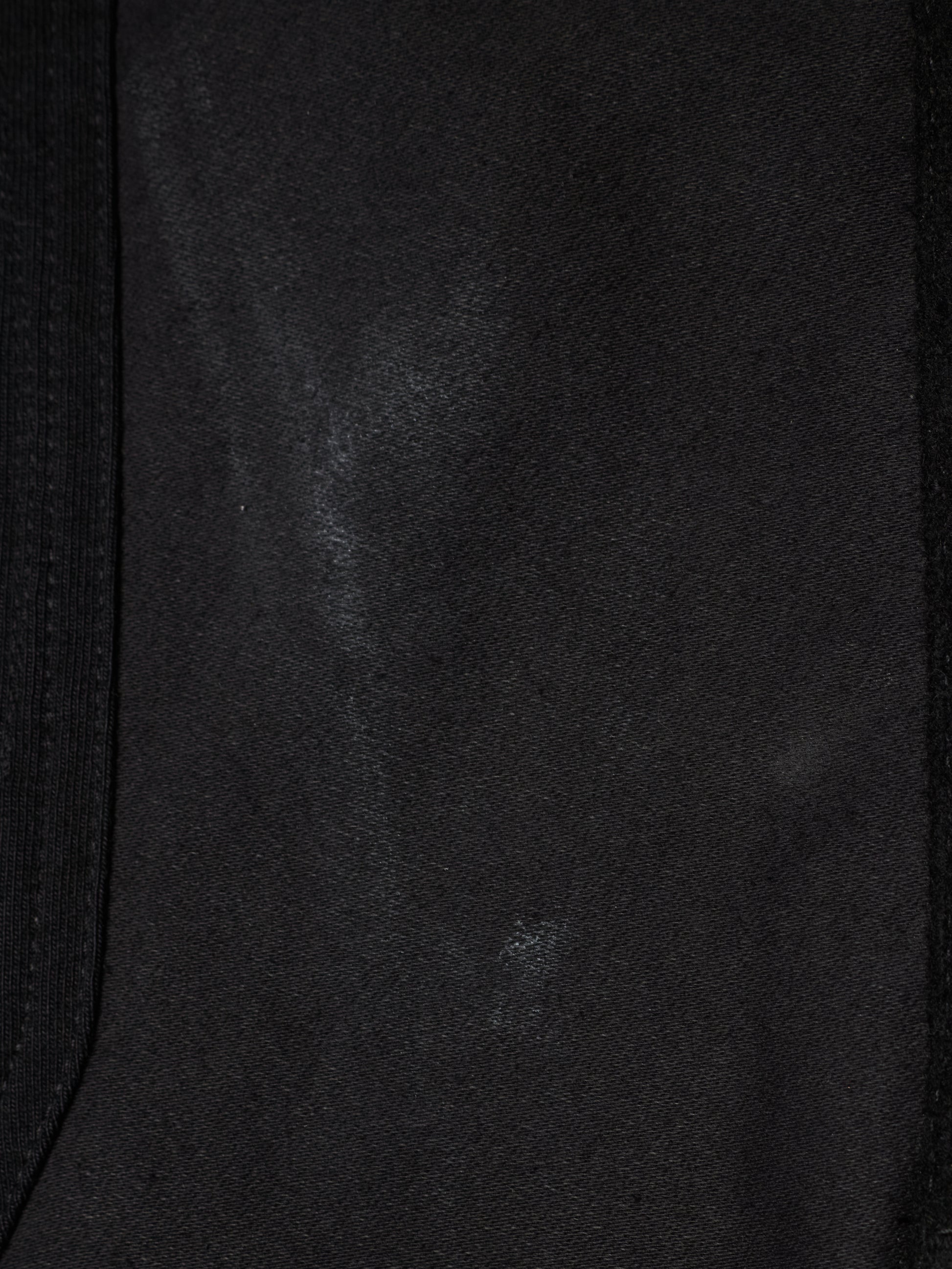 Close-up of a black fabric surface with a subtle sheen and a dark ribbed trim along the left and right edges.