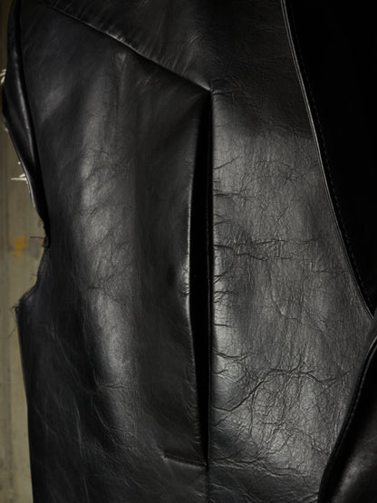 Close-up of a black leather jacket showing the textured grain and stitched panel seams.
