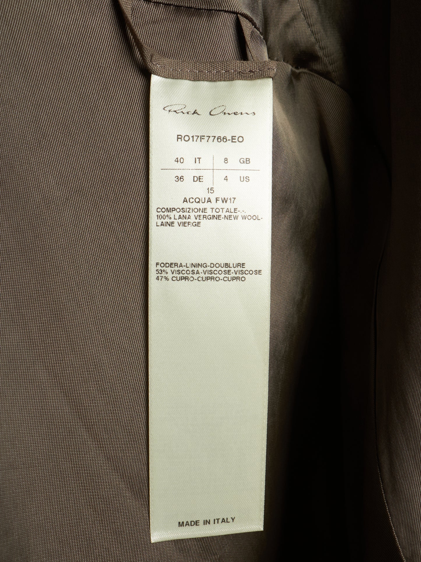 A close-up of a garment's interior label reading 'Rich Queen's' with product code 'R017F7765-EO' and 'MADE IN ITALY', attached to a dark brown fabric garment.