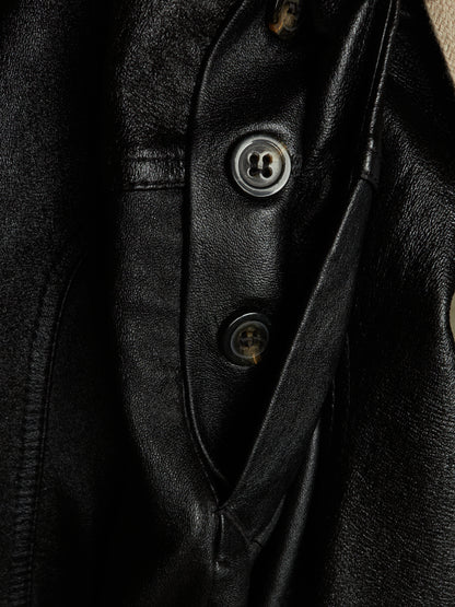Close-up of a black leather jacket showing the buttoned placket and textured leather fabric.