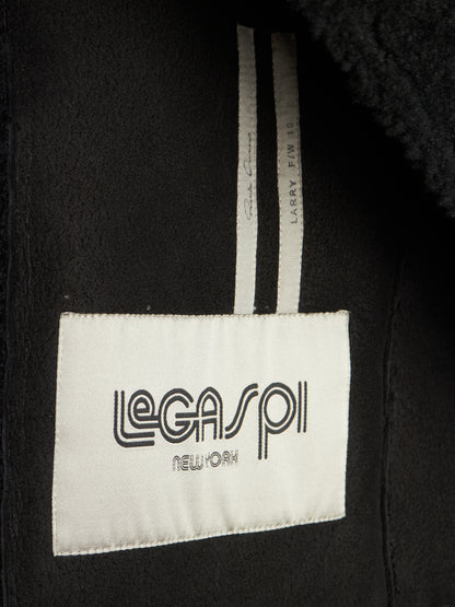Close-up of a black garment interior showing a white sewn-in label that reads 'LEGASP1 NEW YORK' and a striped inner tag.