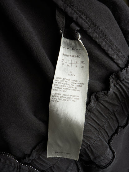 Close-up of a black garment interior showing a sewn-on size and care label that reads Rich Coast and R019F5882-SD.