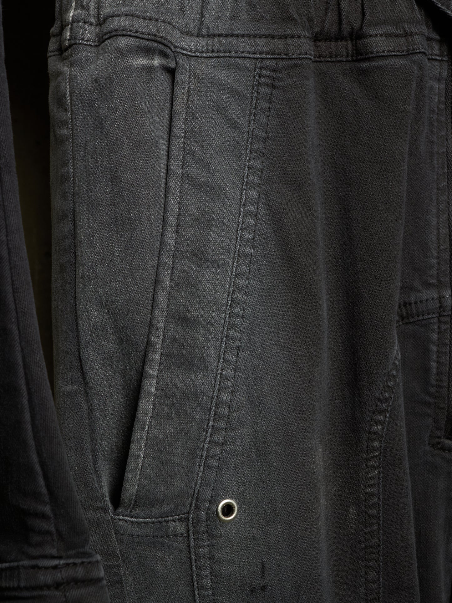 Close-up of dark charcoal gray canvas fabric with a side pocket and metal grommet detail.