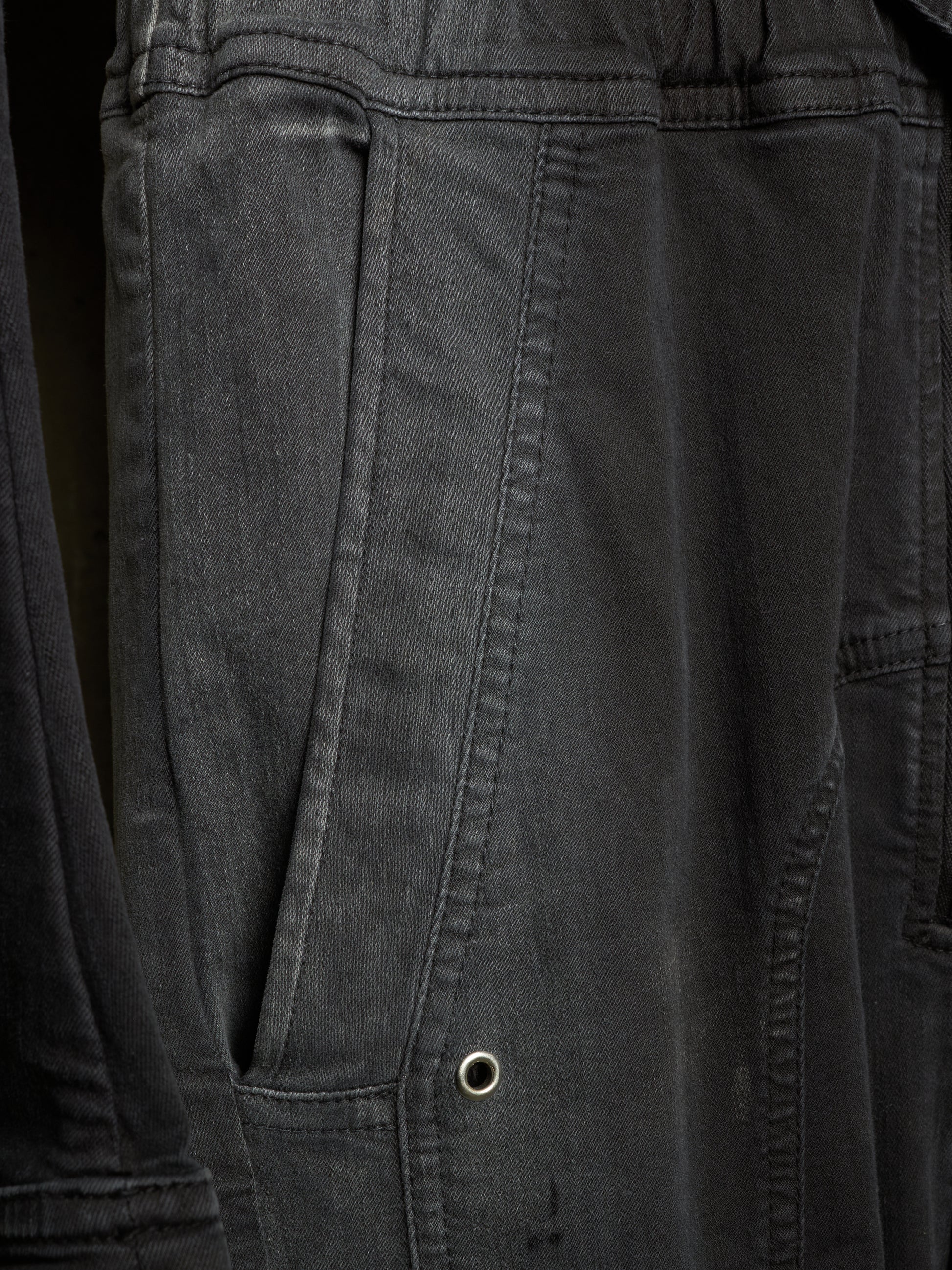 Close-up of dark charcoal gray canvas fabric with a side pocket and metal grommet detail.