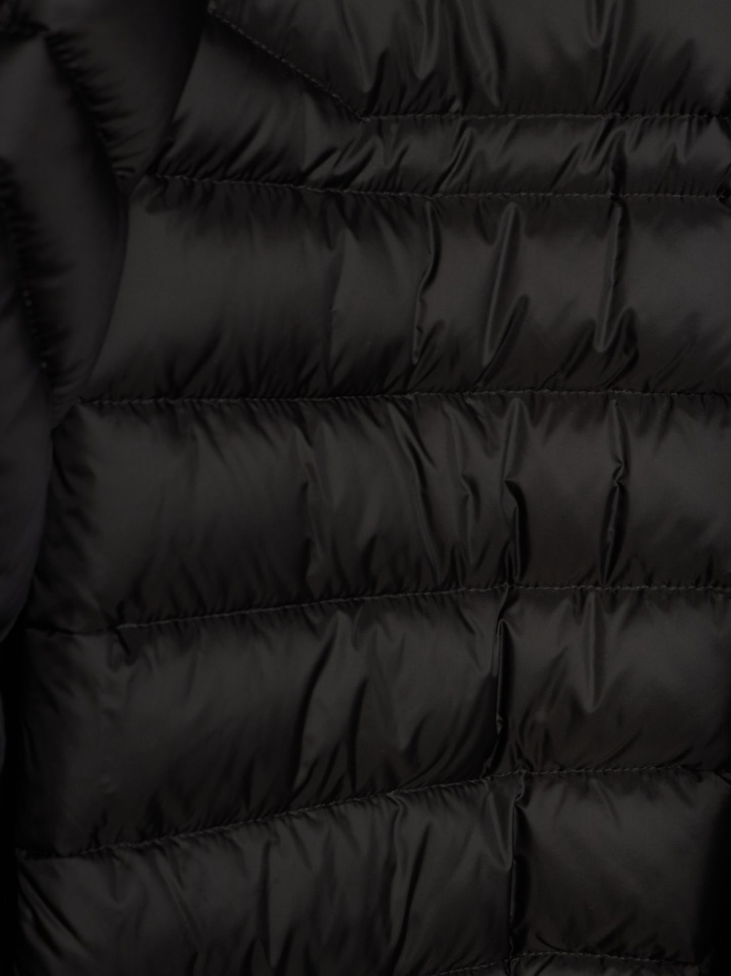 Close-up of a black puffer jacket showing horizontal quilting and a smooth, slightly shiny fabric texture.