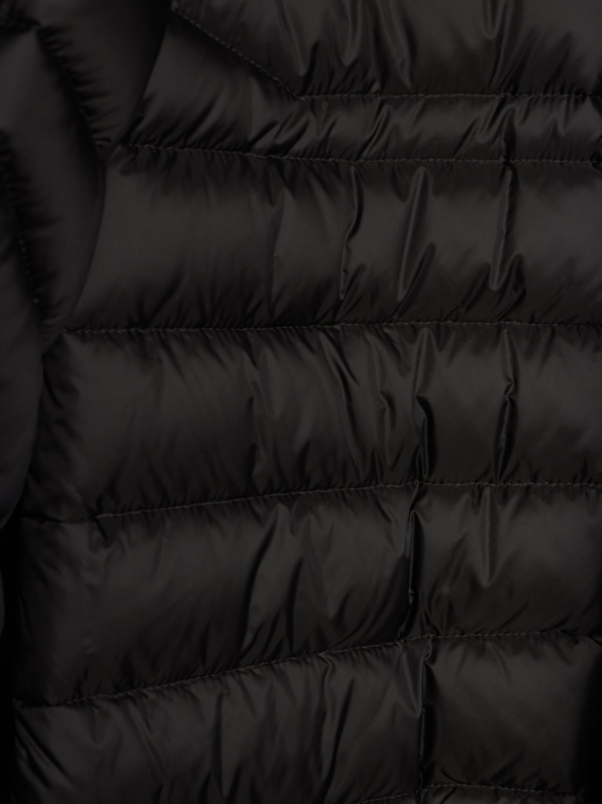 Close-up of a black puffer jacket showing horizontal quilting and a smooth, slightly shiny fabric texture.