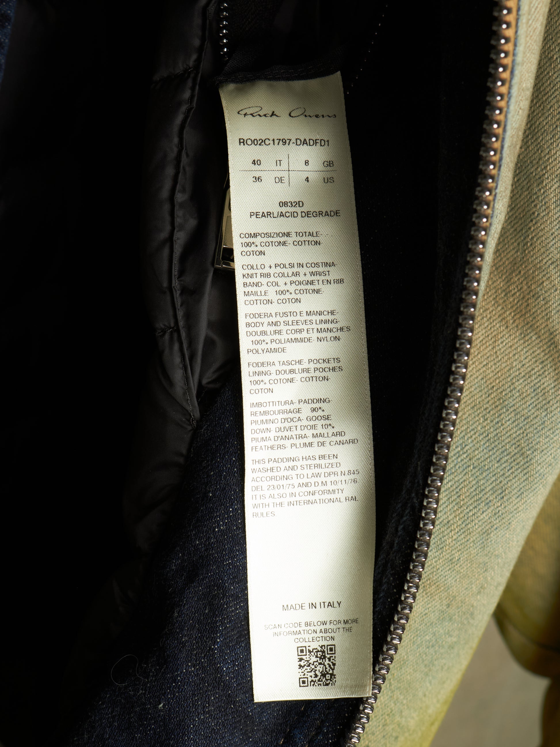 A close-up of a garment's interior zipper opening showing a white fabric care label with printed text, including the brand name 'Faithfull' and product details.