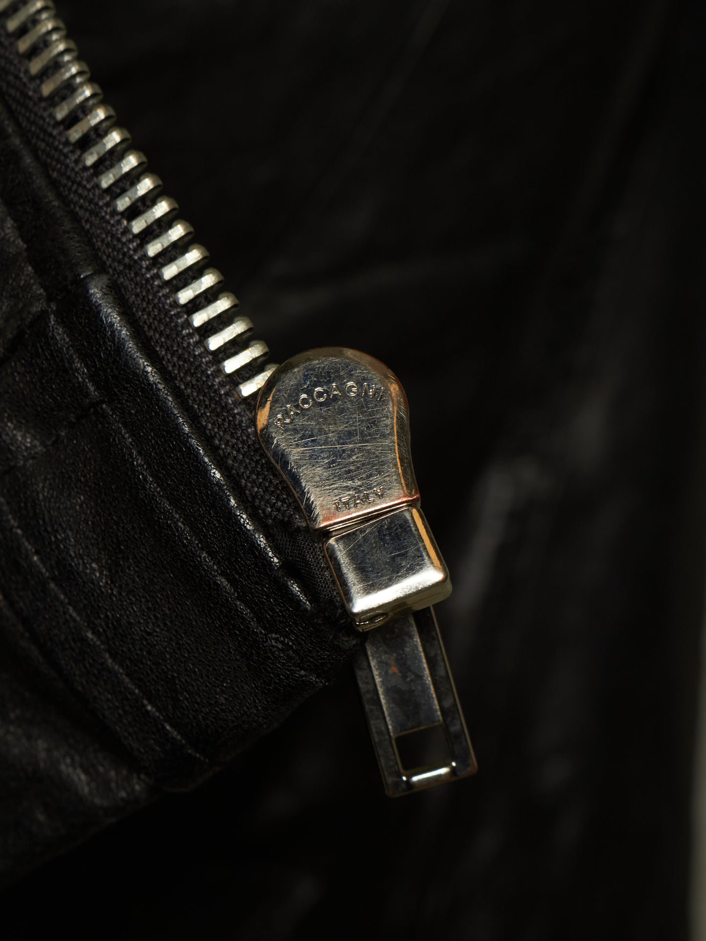 Close-up of a black leather zipper with a silver-toned metal pull tab engraved with the brand name 'GOGOLD'.