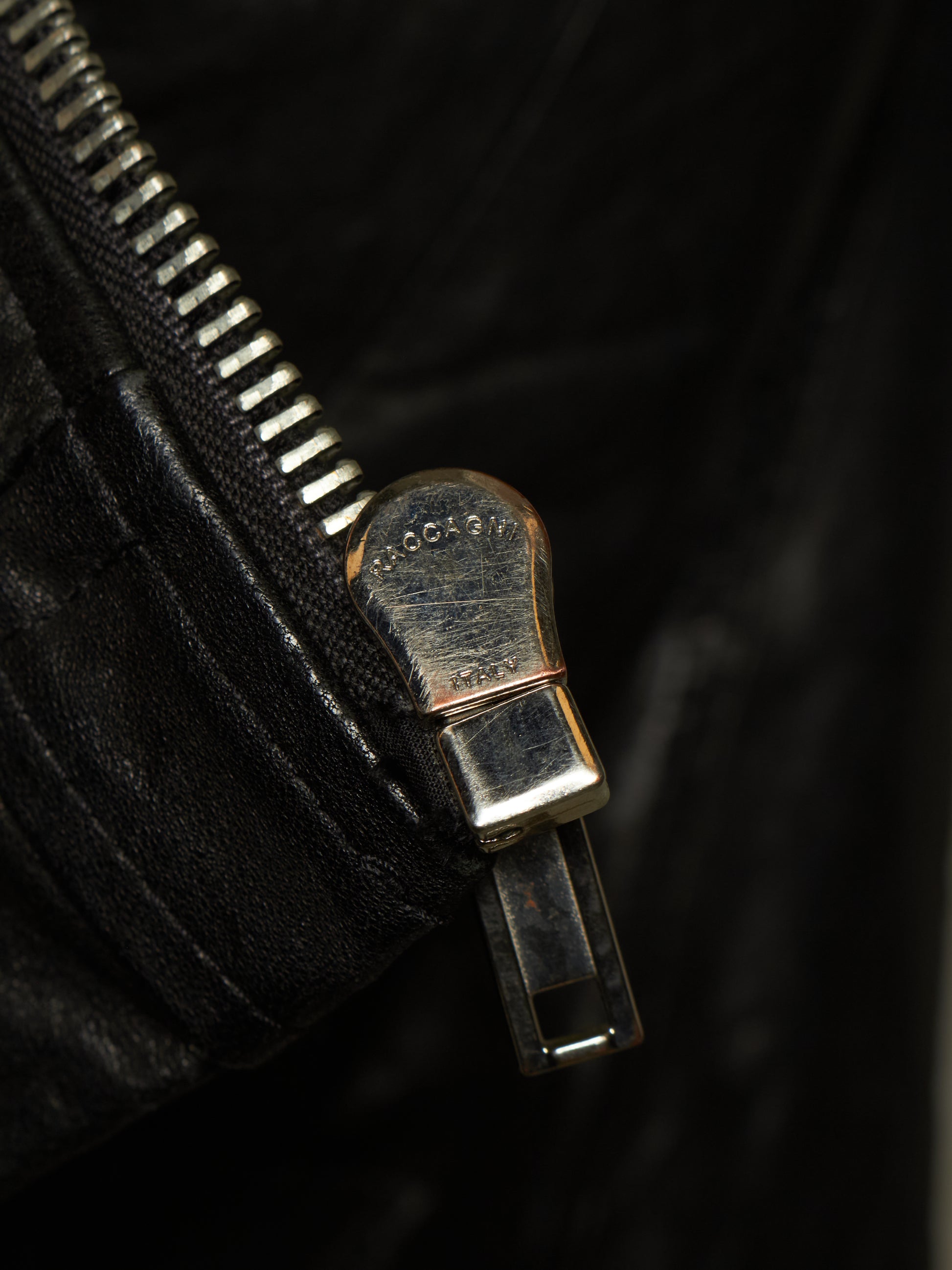 Close-up of a black leather zipper with a silver-toned metal pull tab engraved with the brand name 'GOGOLD'.
