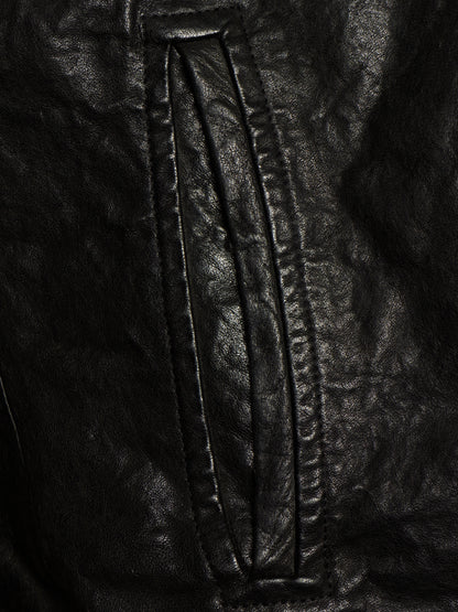 Close-up of a black leather jacket showing a vertical seam and stitched panel detail.