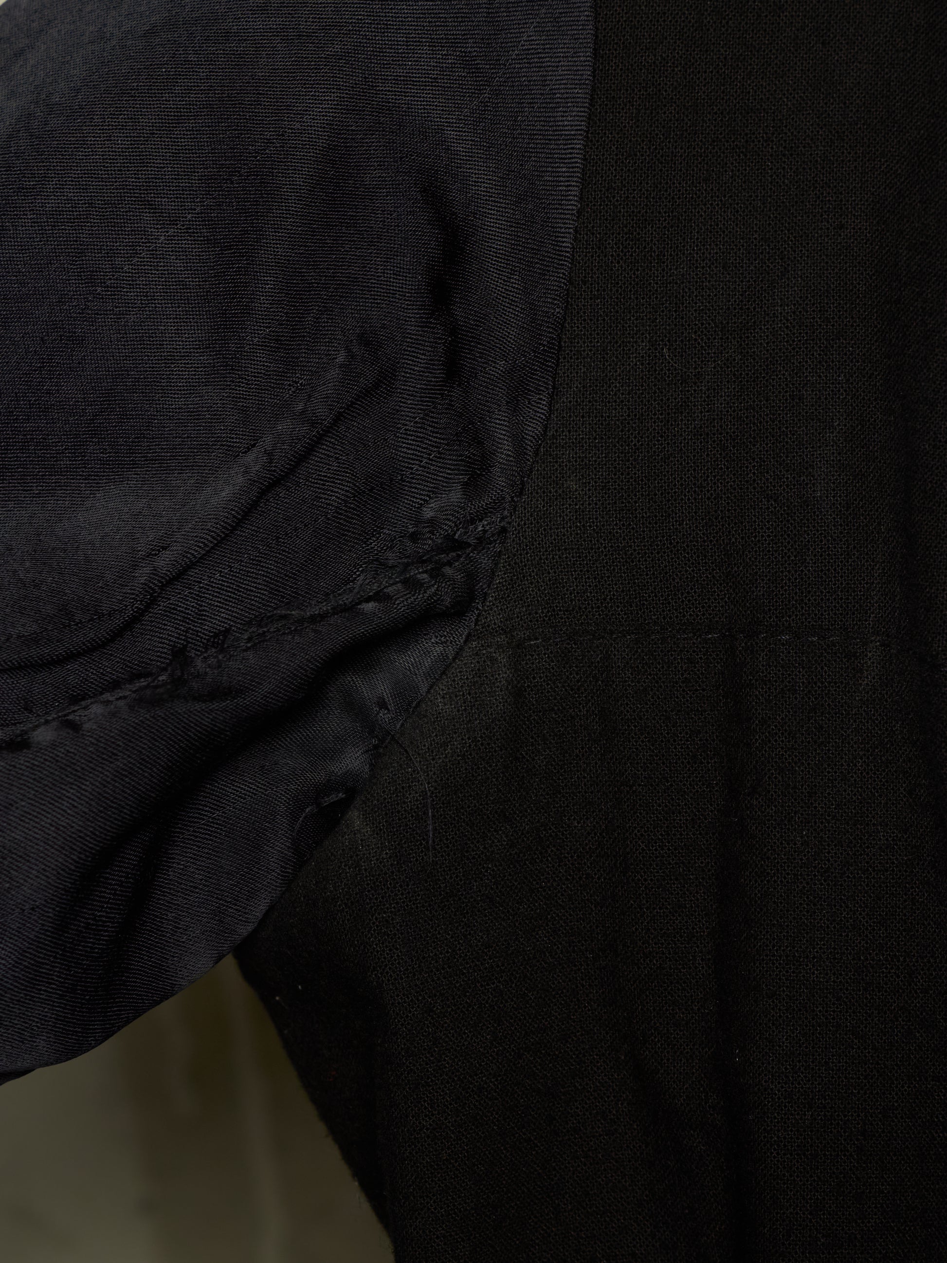 Close-up detail of a black garment showing a sleeve attachment and stitched seam.