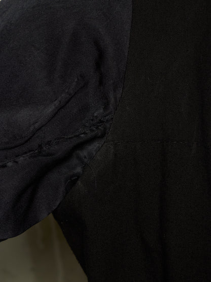 Close-up detail of a black garment showing a sleeve attachment and stitched seam.