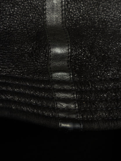 Close-up of black textured leather with a central stitched seam and horizontal stitched detailing.