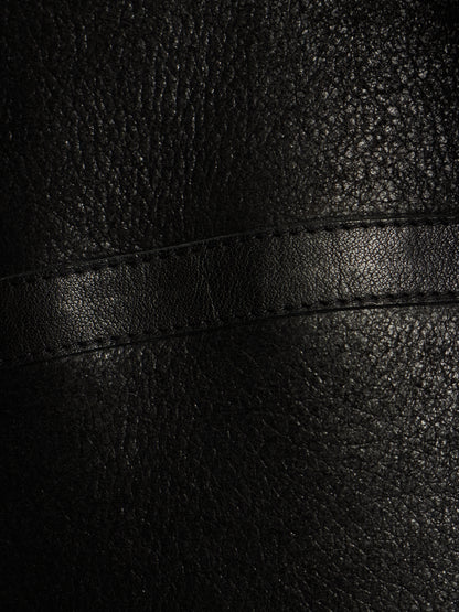 Close-up of black textured leather with a horizontal stitched seam.
