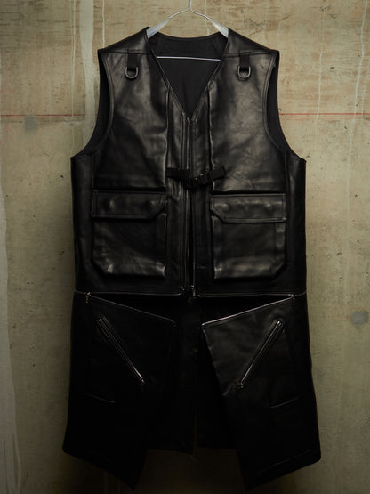 A black leather utility vest with multiple zippered and flap pockets, hanging on a white hanger against a textured concrete wall.