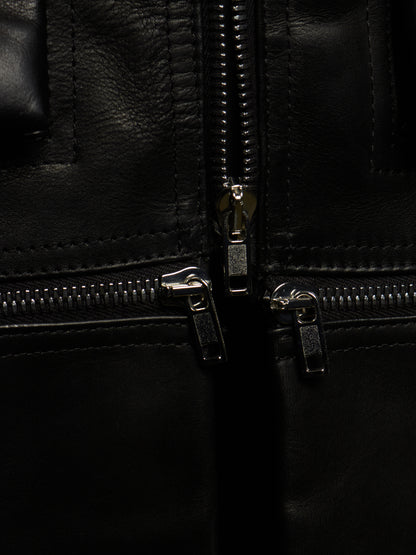 Close-up detail of a black leather jacket showing silver metal zippers and stitching.