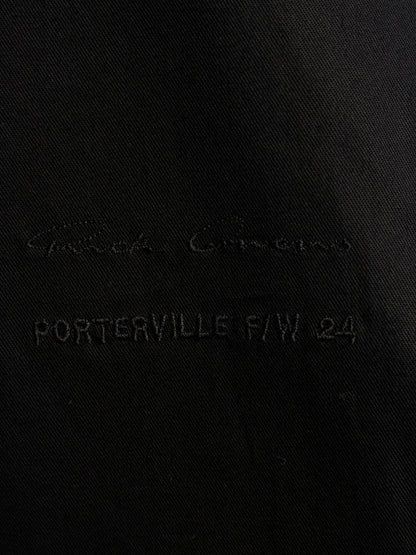 Close-up of a black fabric surface with tonal embroidered text reading 'Giorgio Armani' and 'PORTERVILLE F/W 24'.