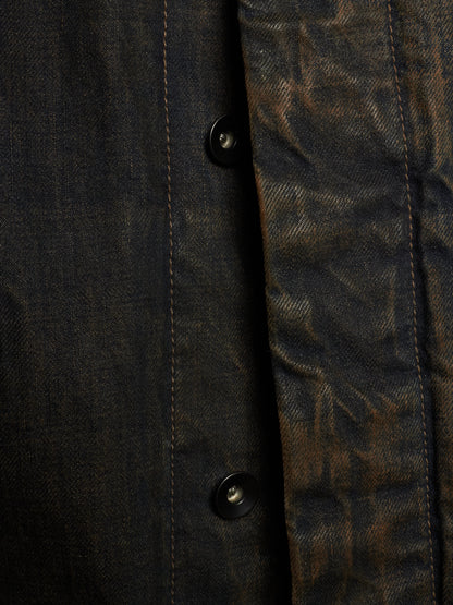 Close-up of a dark textured button-up shirt with a heavily distressed, mottled finish in black and brown tones.