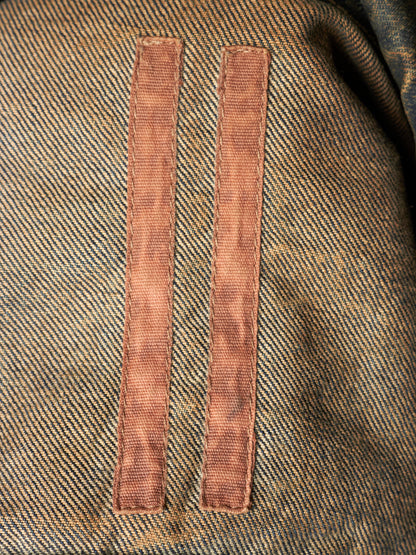 Close-up of a textured tweed fabric in brown and beige with two vertical rose-gold metal loops attached near the center.