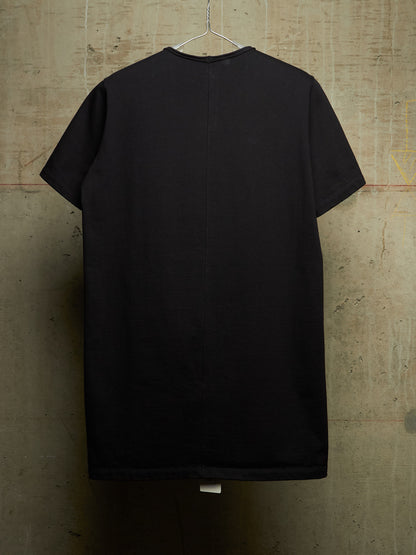 A black short-sleeve t-shirt hanging on a metal hanger against a textured concrete wall.