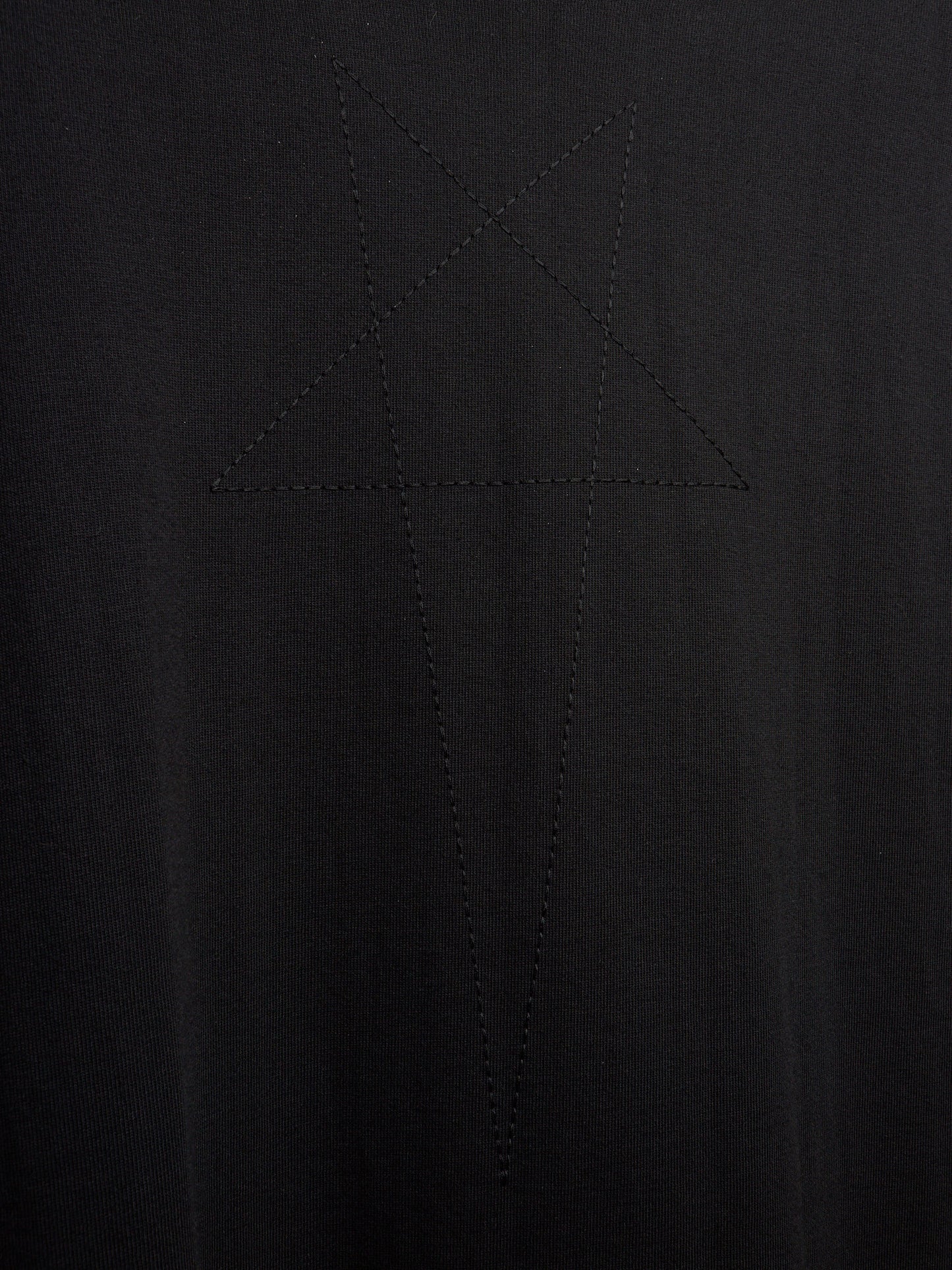 Close-up of a black ribbed knit fabric with a tonal embroidered or stitched star-like geometric motif in the center.