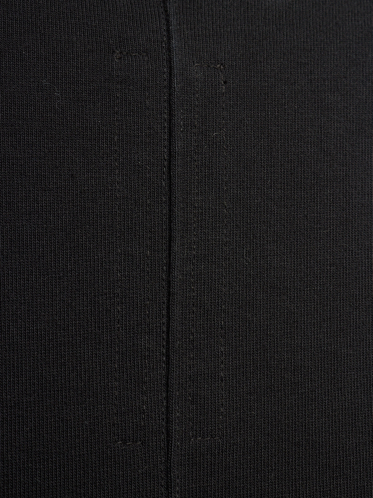 Close-up of a black textured knit fabric with a central seam running vertically.