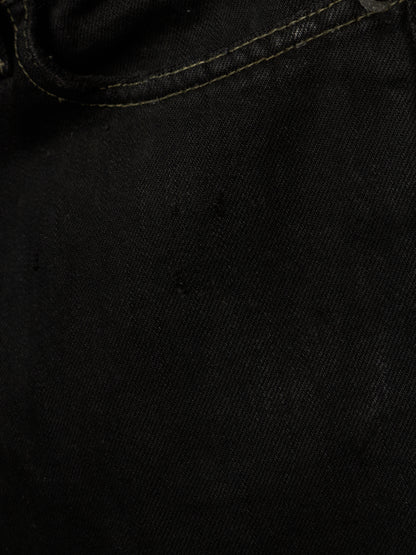 Close-up of black denim fabric with visible twill texture and a curved seam line.