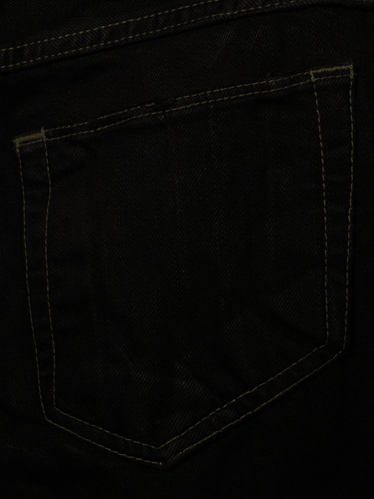 Close-up of a black denim pocket with contrasting tan stitching.