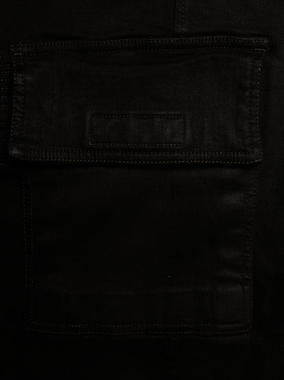 Close-up of a black leather or faux-leather pocket with visible stitching and a small rectangular patch on the flap.