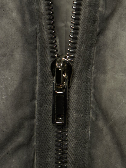 Close-up of a dark gray textured fabric jacket with a black metal zipper running vertically down the center.