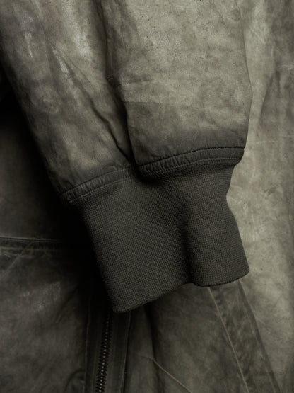 Close-up detail of a dark gray suede or nubuck jacket sleeve with ribbed knit cuff and a zipper seam.