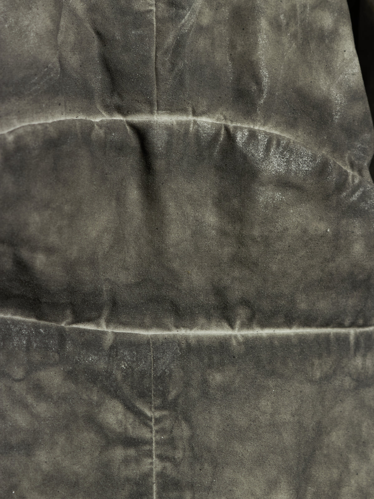 A close-up of a dark gray textured fabric with visible folds and a horizontal seam.